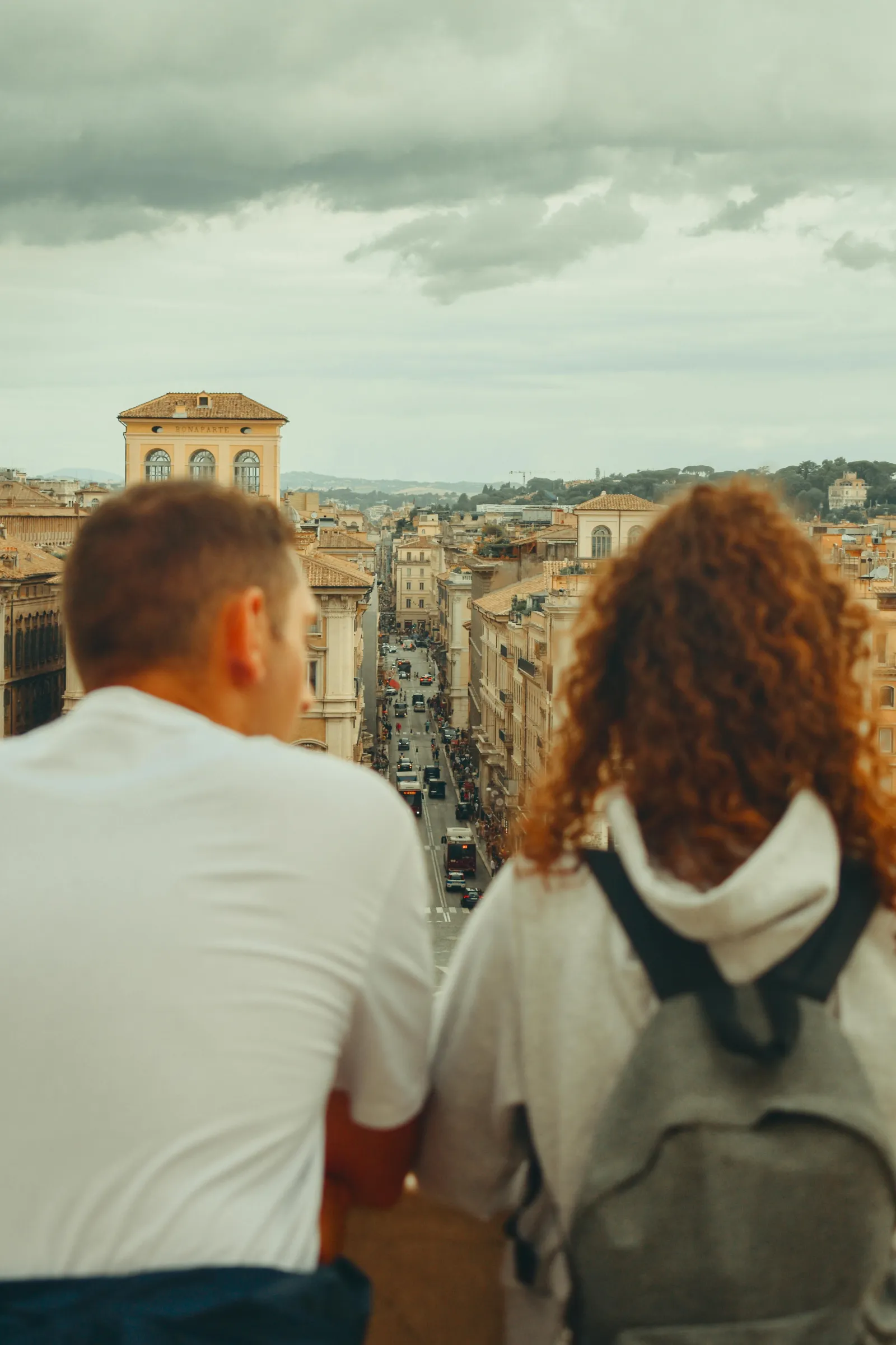 Et par på byferie står med ryggen til og ser utover takene i Roma